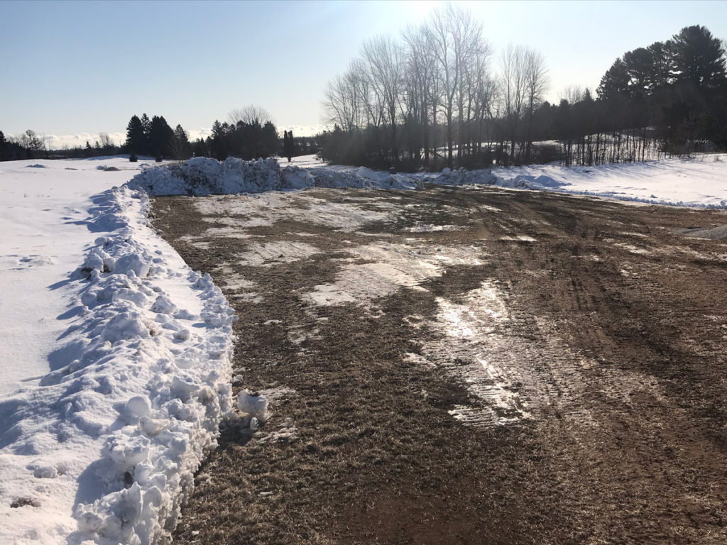 a freshly excavated path in the snow with exposed dirt