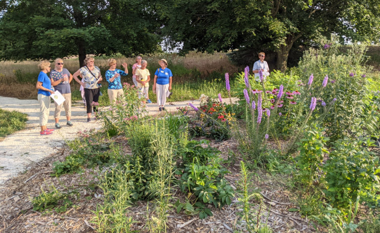 a group of people discuss a large perennial garden
