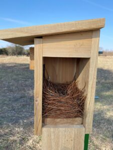 A wooden birdhouse with a bird nest inside