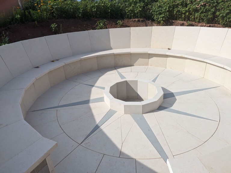 an outdoor sunken stone seating area with a compass on the floor