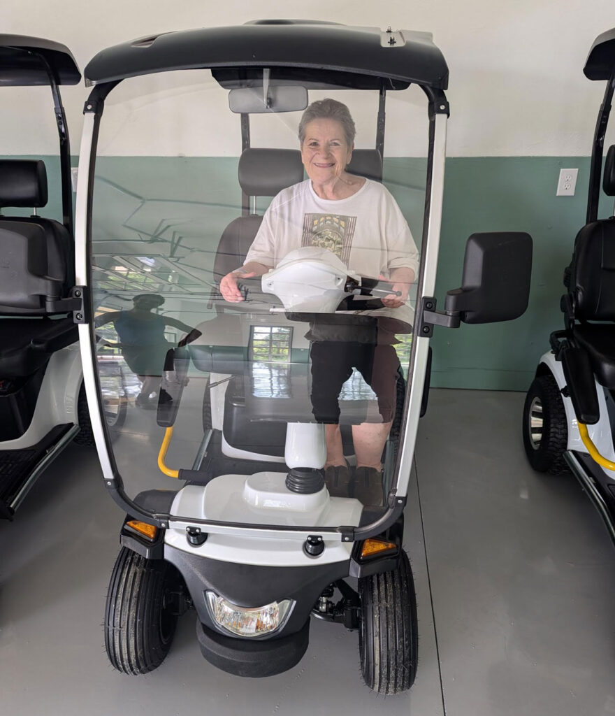 A woman in a modified golf cart parked in a building.