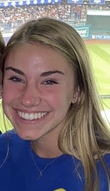 A selfie of a smiling young woman taken in the stands of a sporting arena.