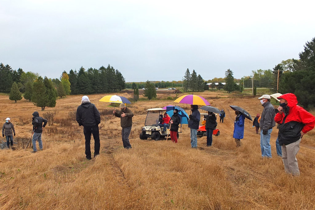 Many people with umbrellas walk in a field.