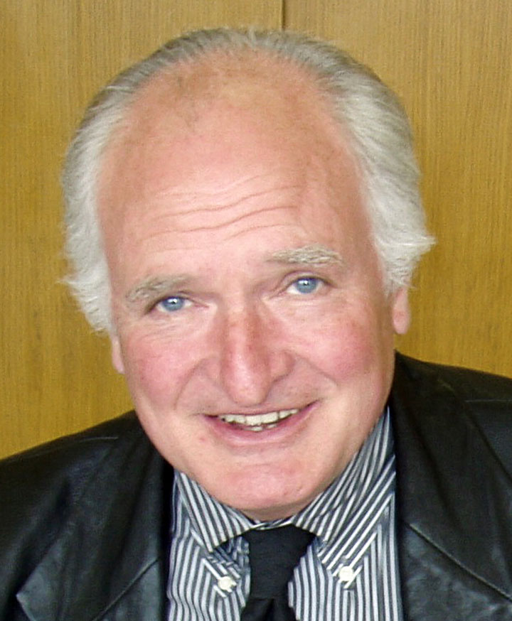 an older caucasian male with white gray hair, blue eyes, and a leather jacket