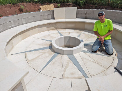 a young man in a safety yellow t-shirt kneels in a circle of stone