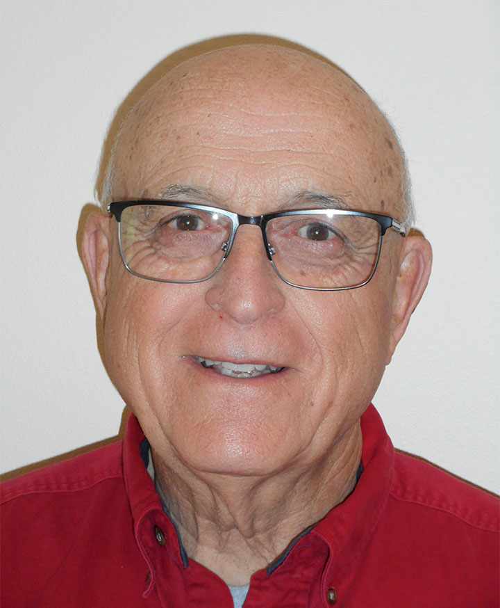 a mature man with a red polo and eyegalsses.